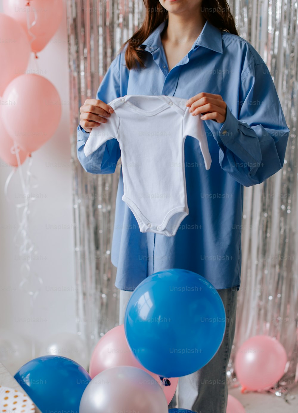 a woman holding a white shirt over a bunch of balloons