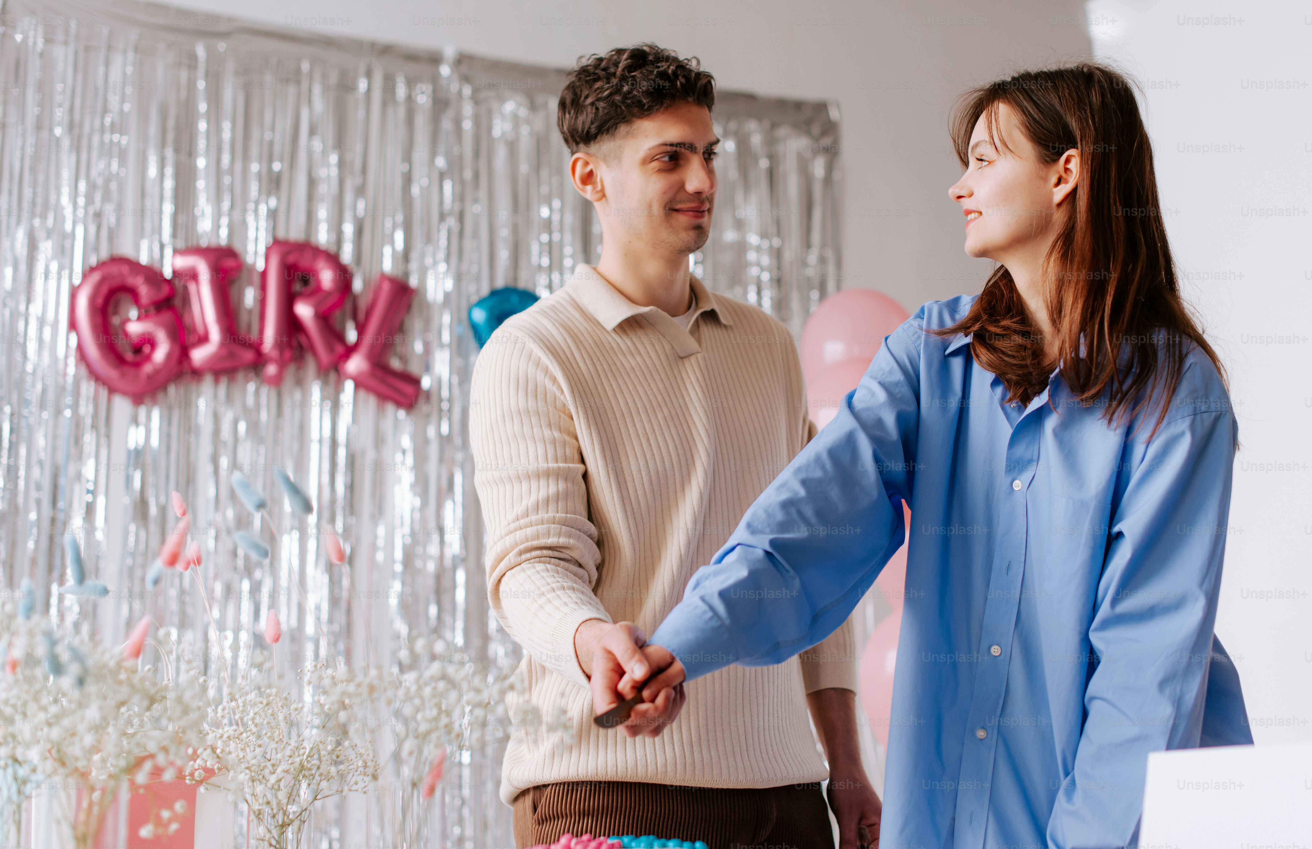 A man and a woman standing in front of a wall with balloons photo ...