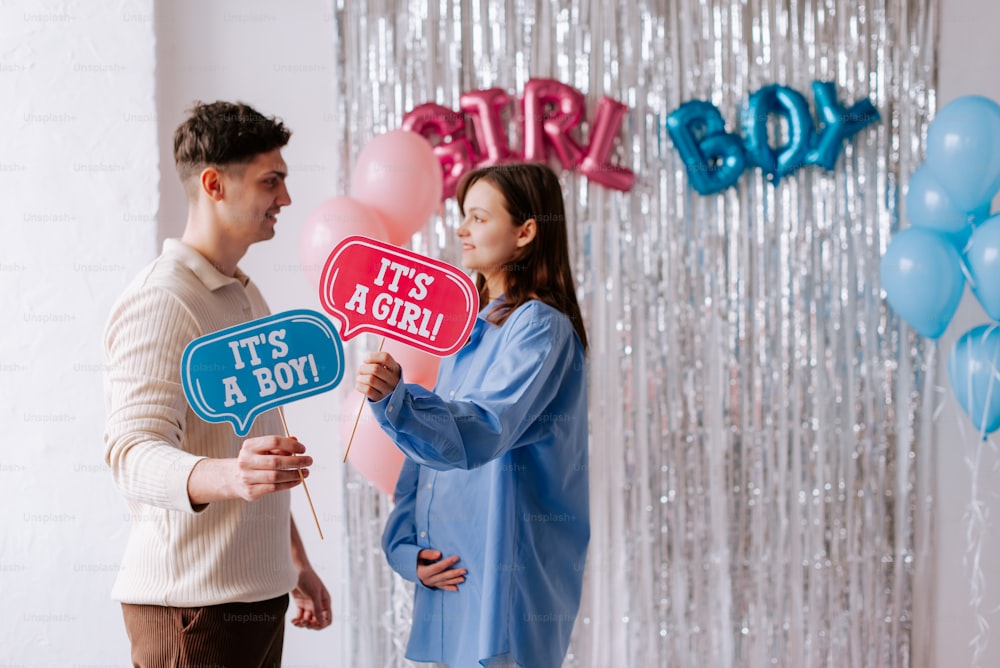 a man and a woman holding up a sign that says it's a boy