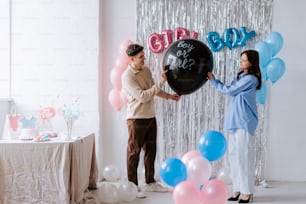 a man and a woman holding balloons in front of a backdrop
