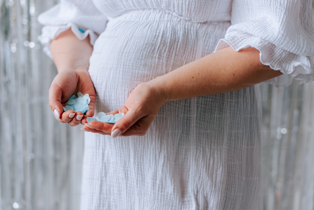 a pregnant woman in a white dress holding a pill