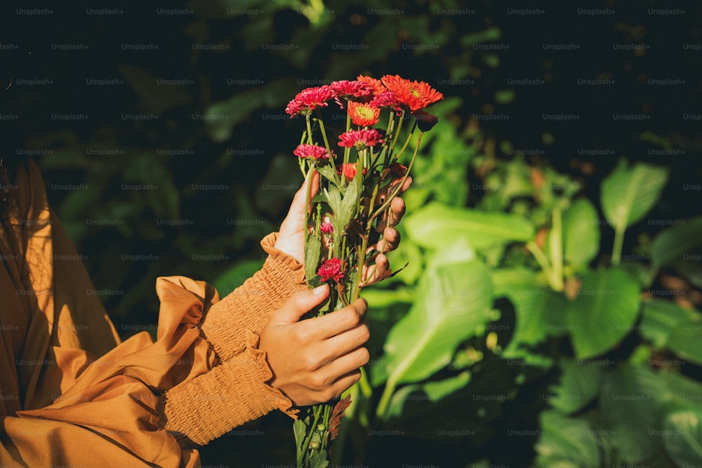 eine Frau hält einen Strauß roter Blumen in der Hand