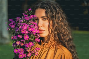 a woman holding a bunch of purple flowers