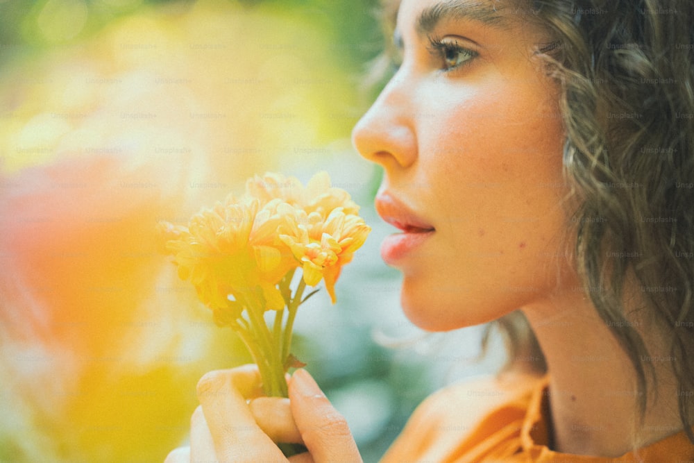 uma mulher segurando uma flor amarela em sua mão