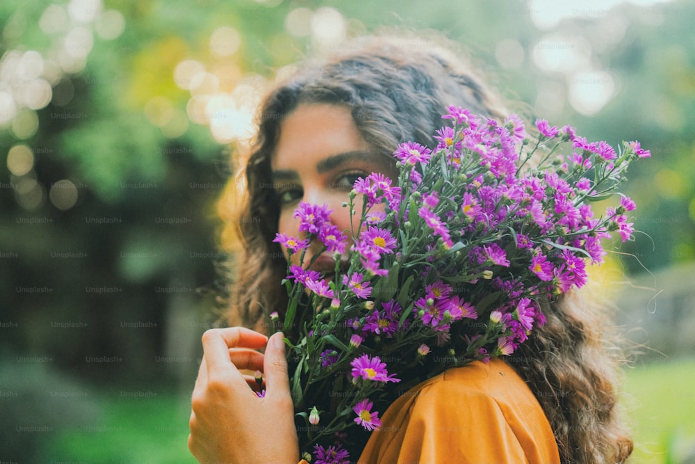 une femme tenant un bouquet de fleurs violettes