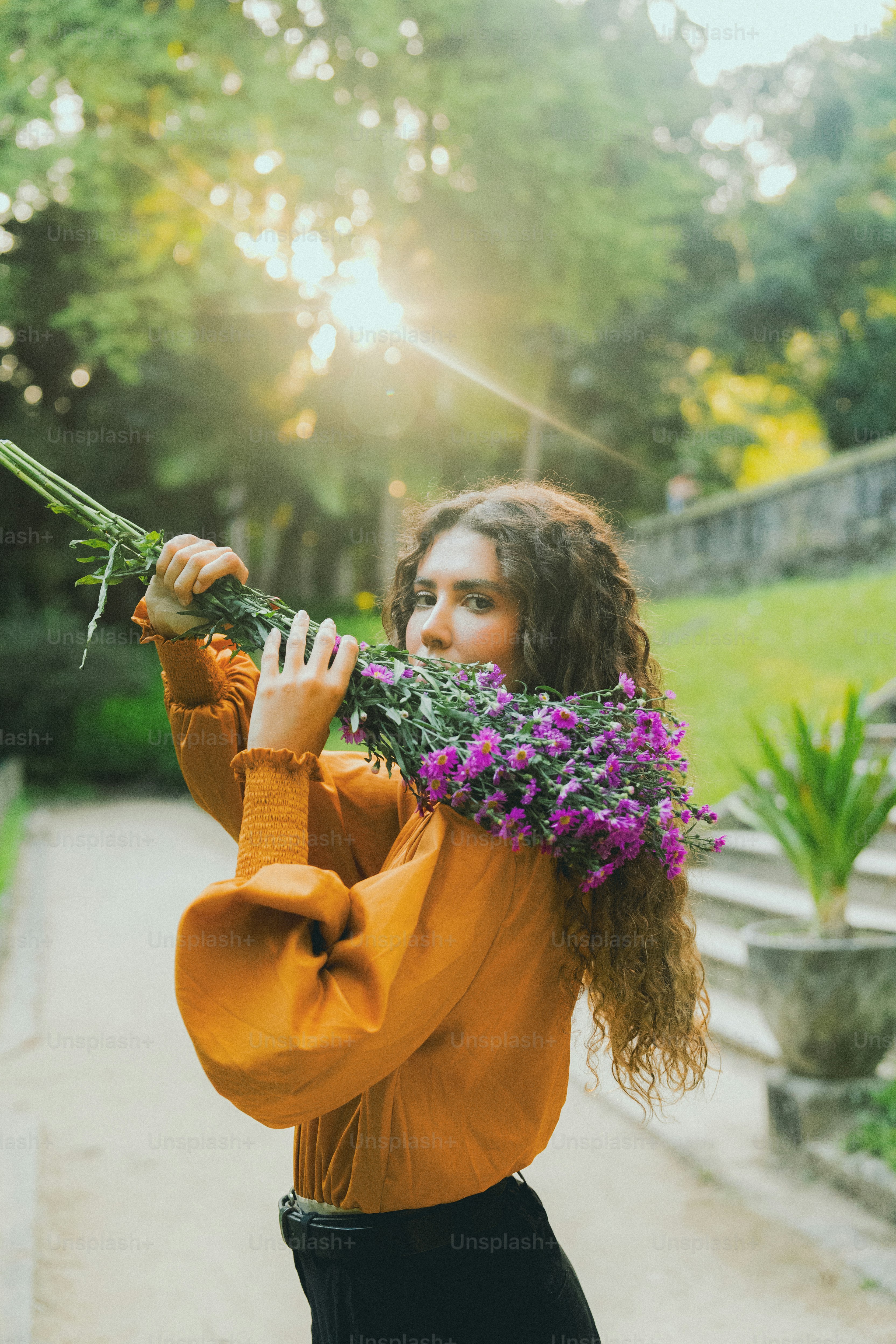 a woman holding a bunch of flowers up to her face