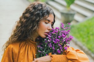 a woman holding a bunch of purple flowers