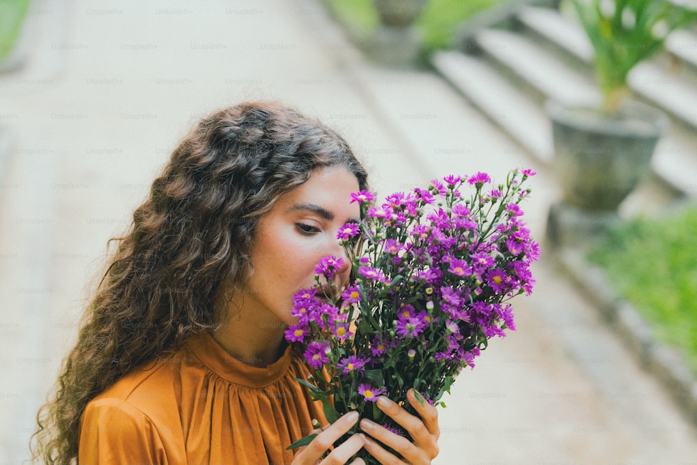 a woman holding a bunch of purple flowers