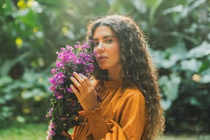 a woman holding a bunch of purple flowers