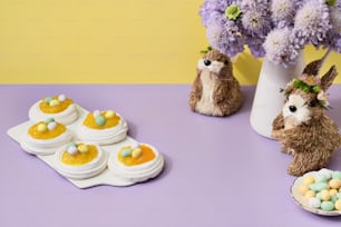 uma mesa roxa coberta com mini ovos e coelhos