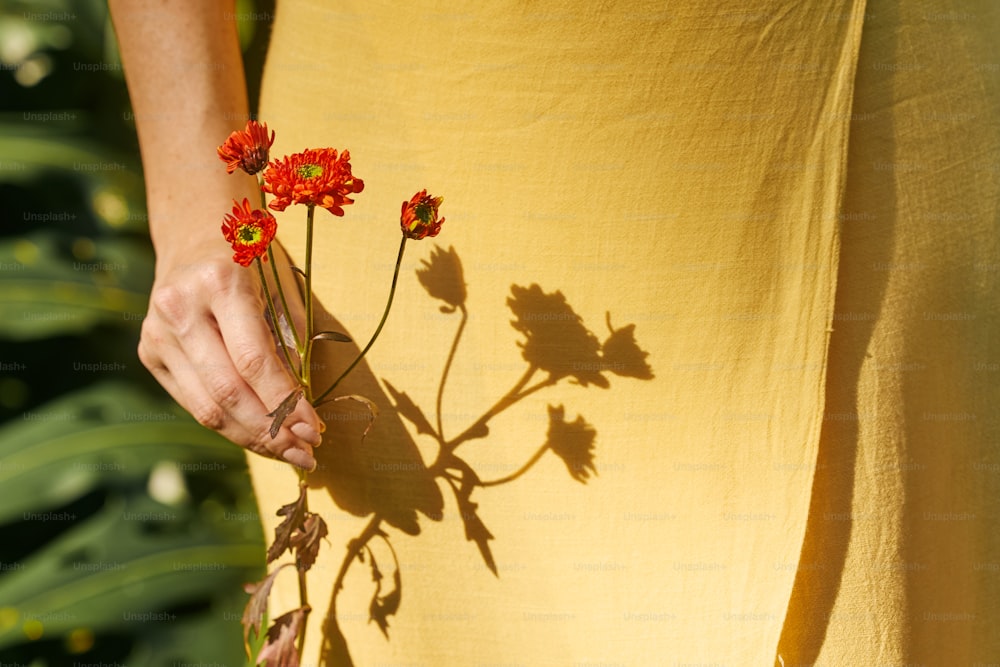 a woman in a yellow dress holding red flowers