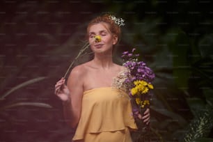 une femme en robe jaune tenant un bouquet de fleurs