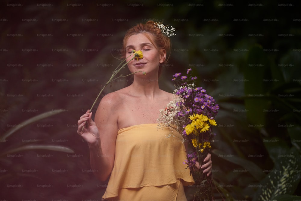eine Frau in einem gelben Kleid hält einen Blumenstrauß in der Hand