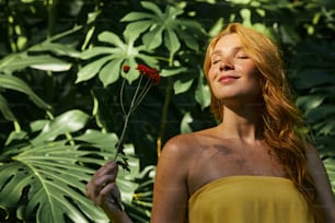 a woman in a yellow dress holding a red flower