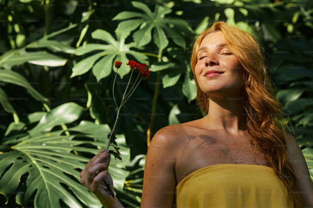 a woman in a yellow dress holding a red flower