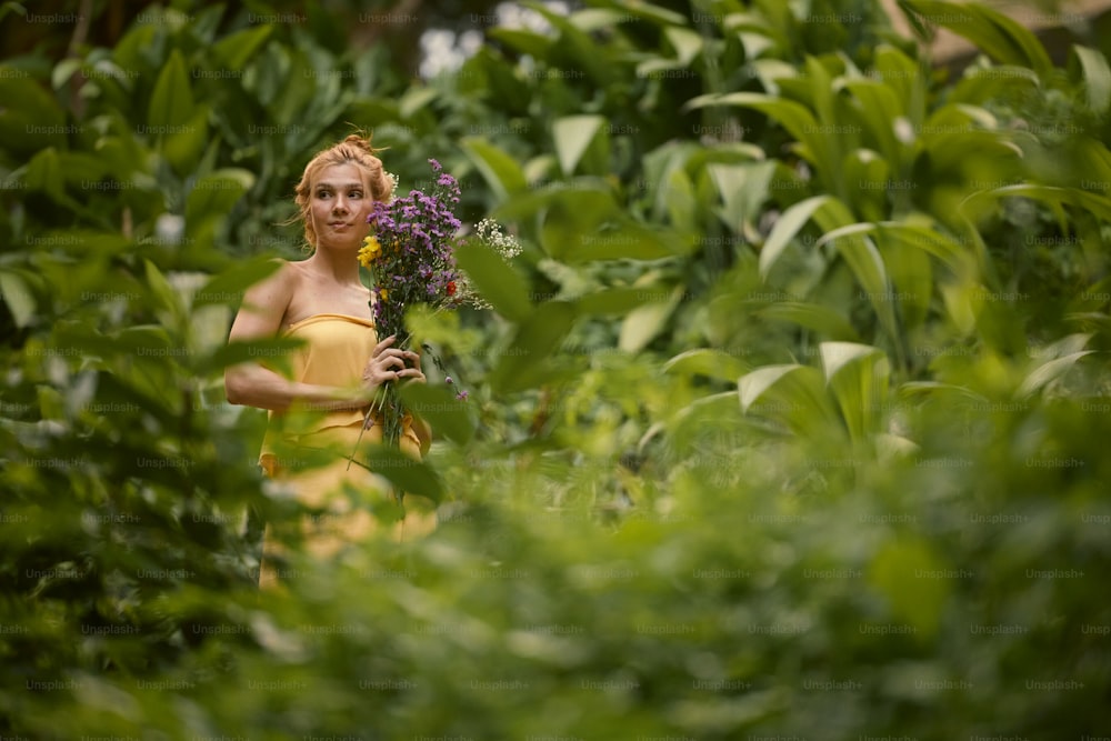 a woman in a yellow dress holding a purple flower