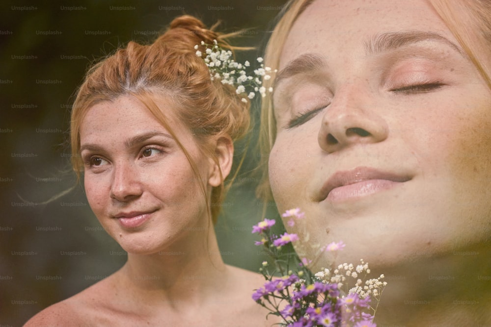a woman with her eyes closed next to another woman with flowers in her hair