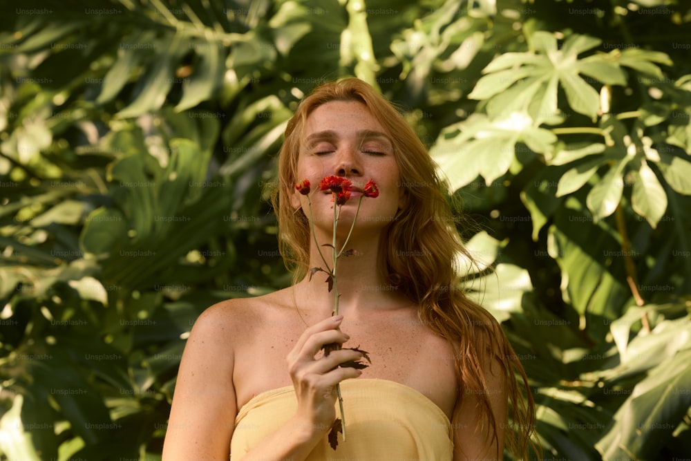 una donna in un vestito giallo che tiene un fiore