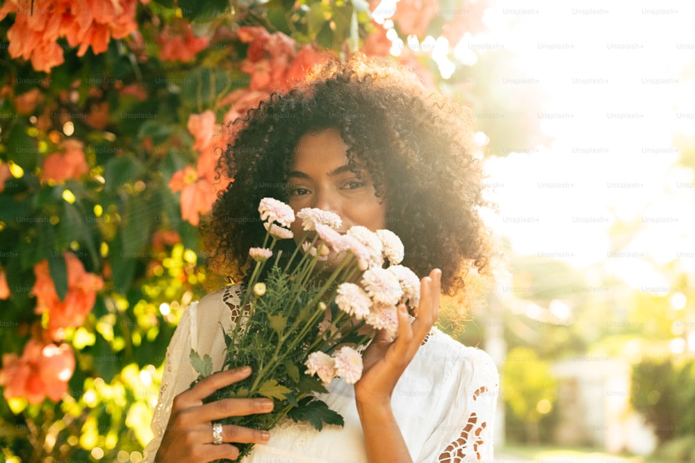 uma mulher segurando um ramo de flores na frente de seu rosto