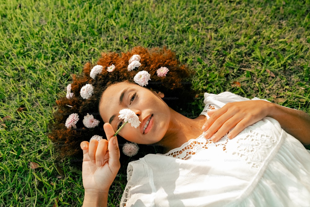 a woman laying on the grass with flowers in her hair