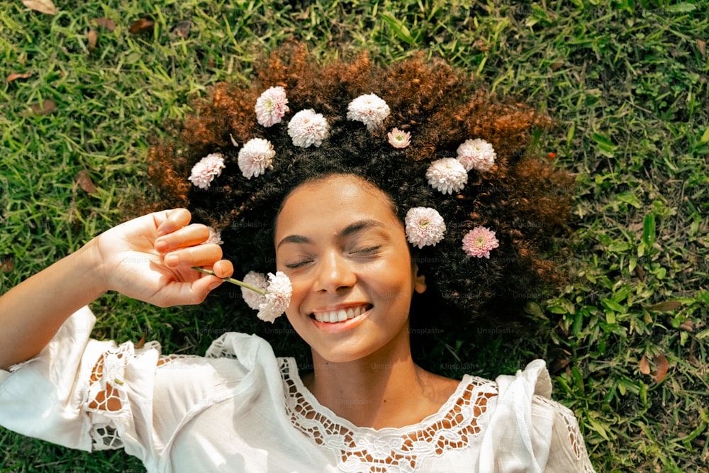 eine Frau, die mit Blumen im Haar im Gras liegt