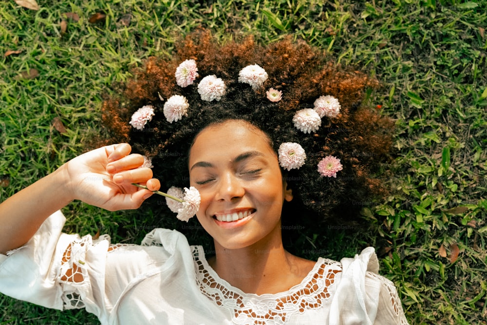 une femme couchée dans l’herbe avec des fleurs dans ses cheveux