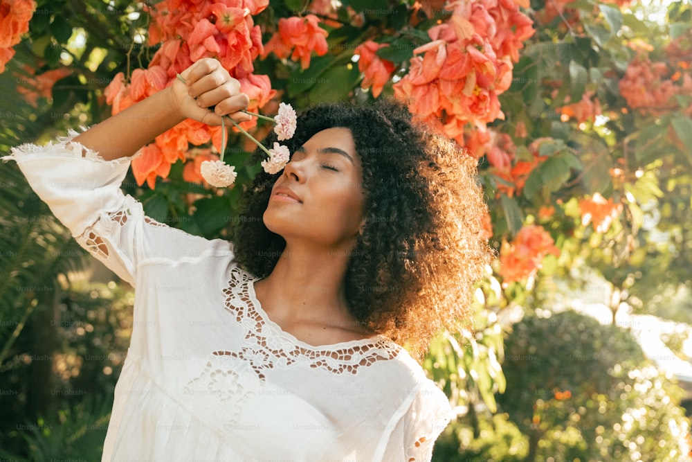 una donna in piedi davanti a un albero con fiori tra i capelli