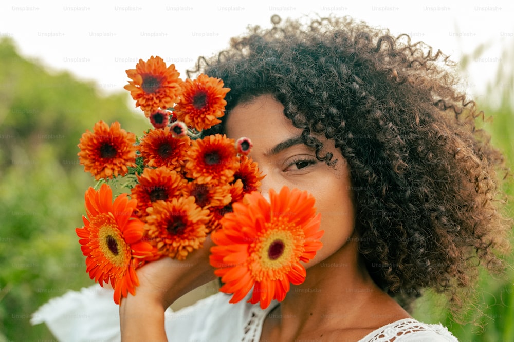une femme tenant un bouquet de fleurs oranger