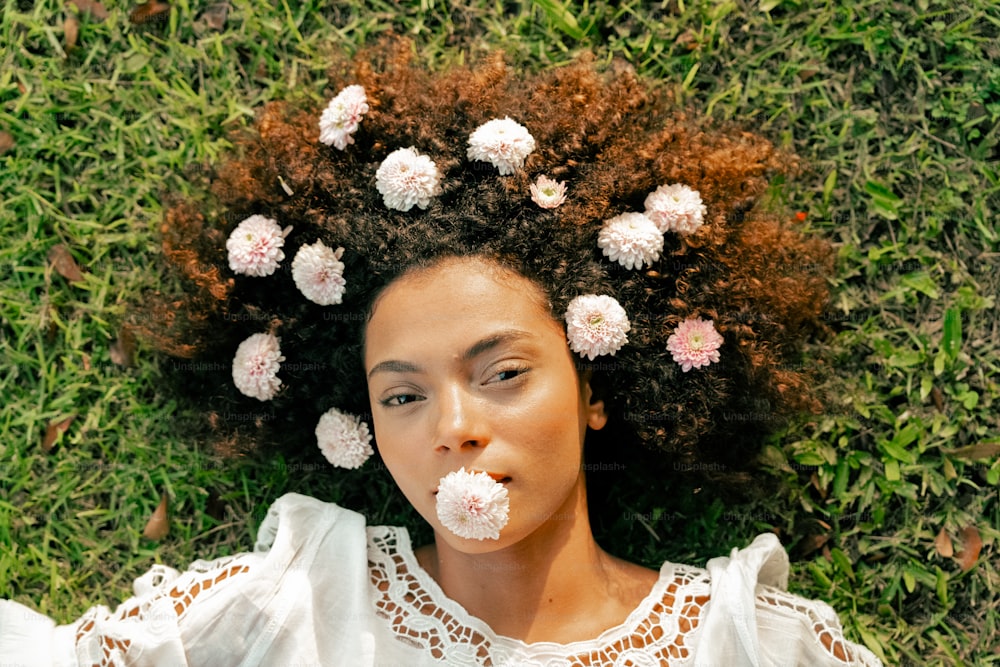 a woman laying on the grass with flowers in her hair