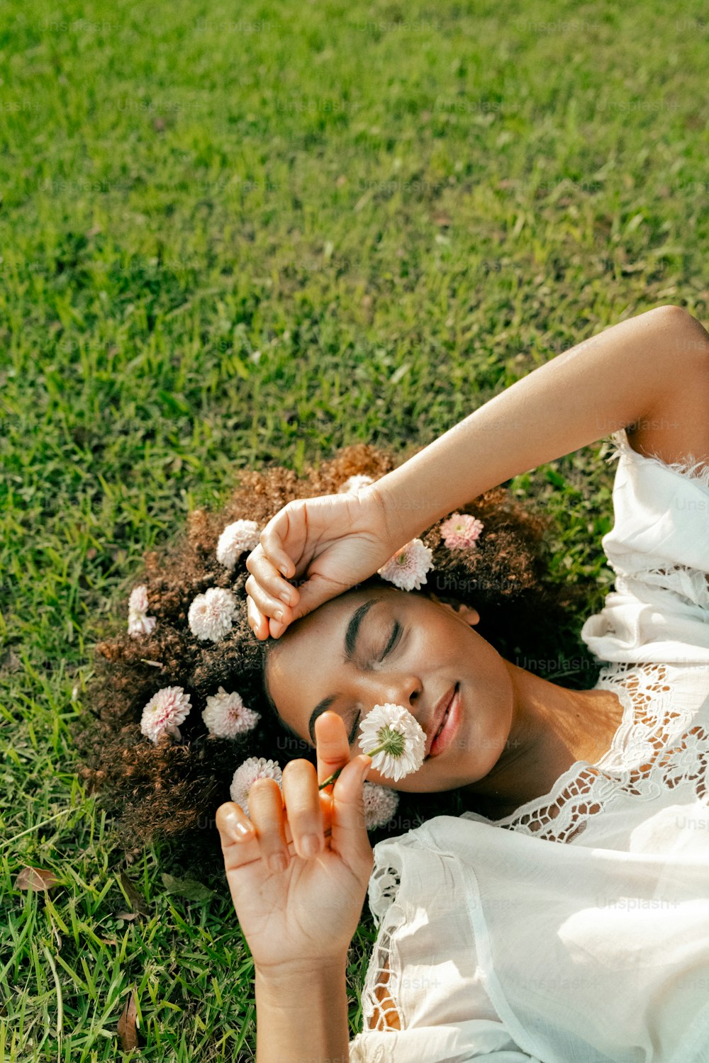 a woman laying in the grass with a flower in her hair