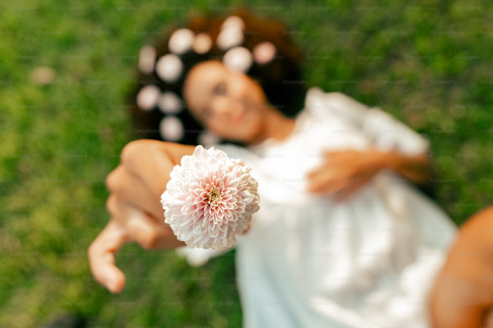 uma mulher segurando uma flor na mão