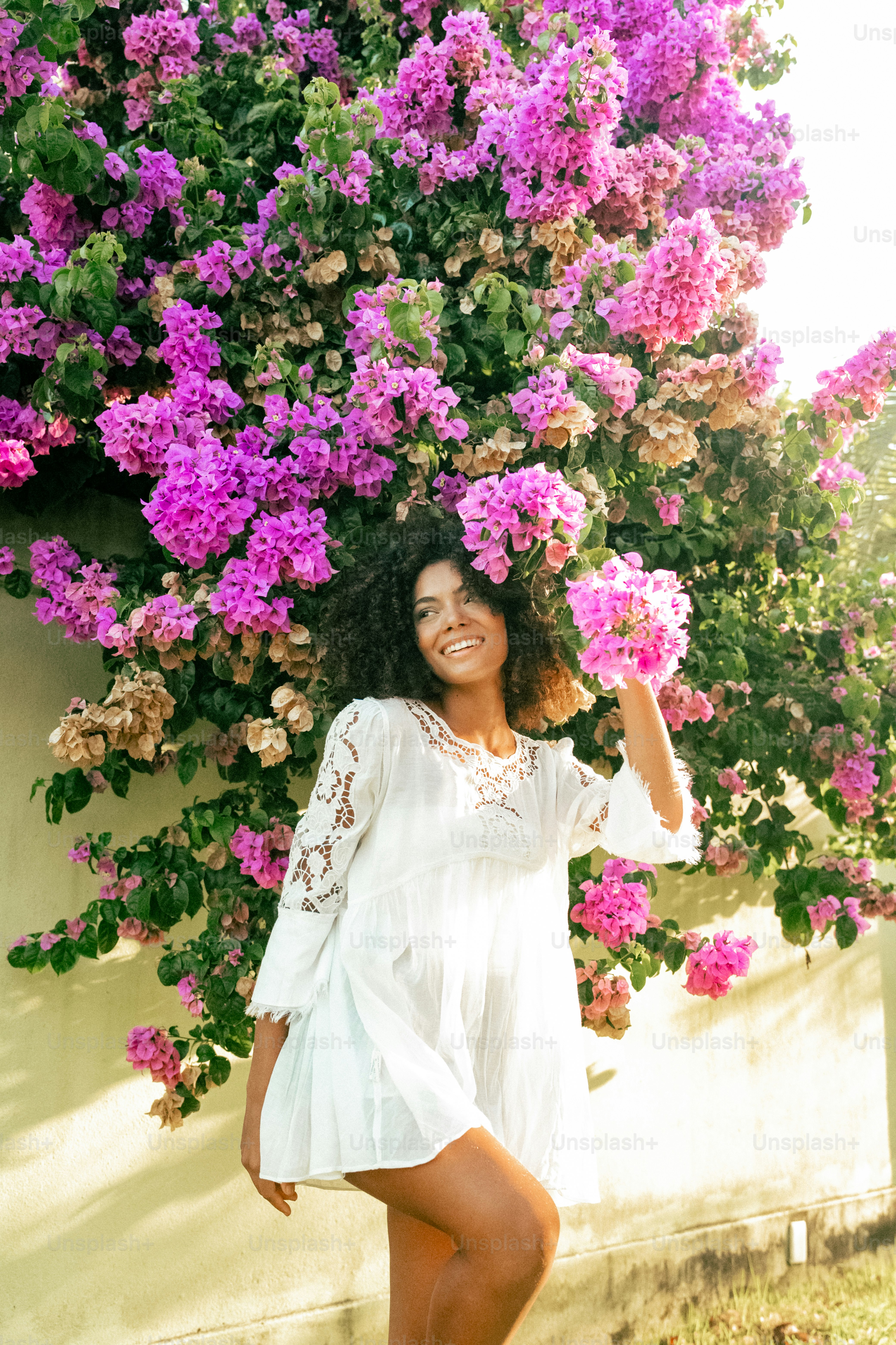 a woman posing in front of a bunch of flowers