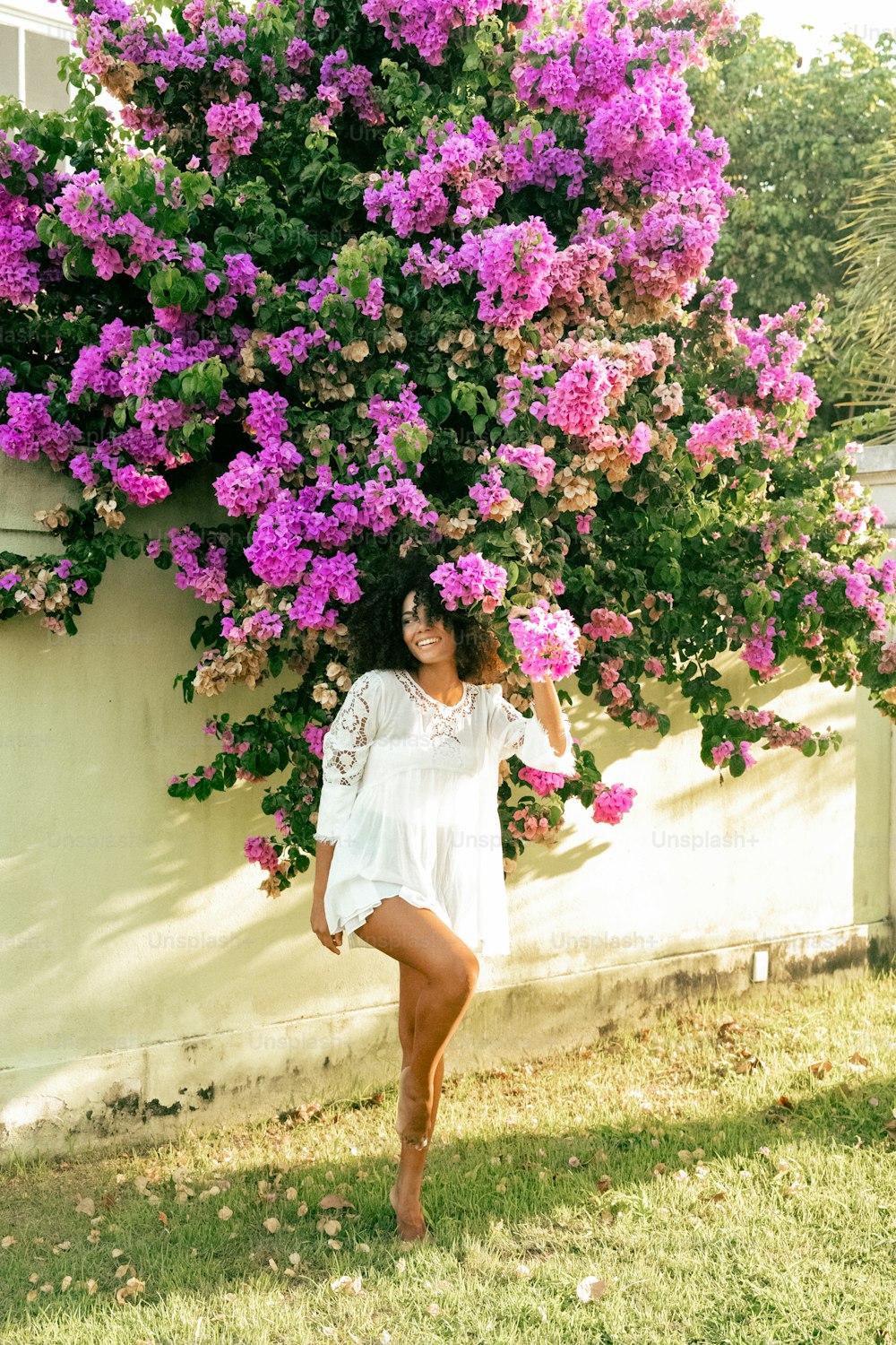 uma mulher em pé na frente de um arbusto de flores