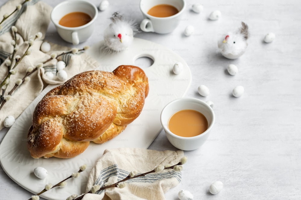 un plato blanco cubierto con un pastel junto a dos tazas de café