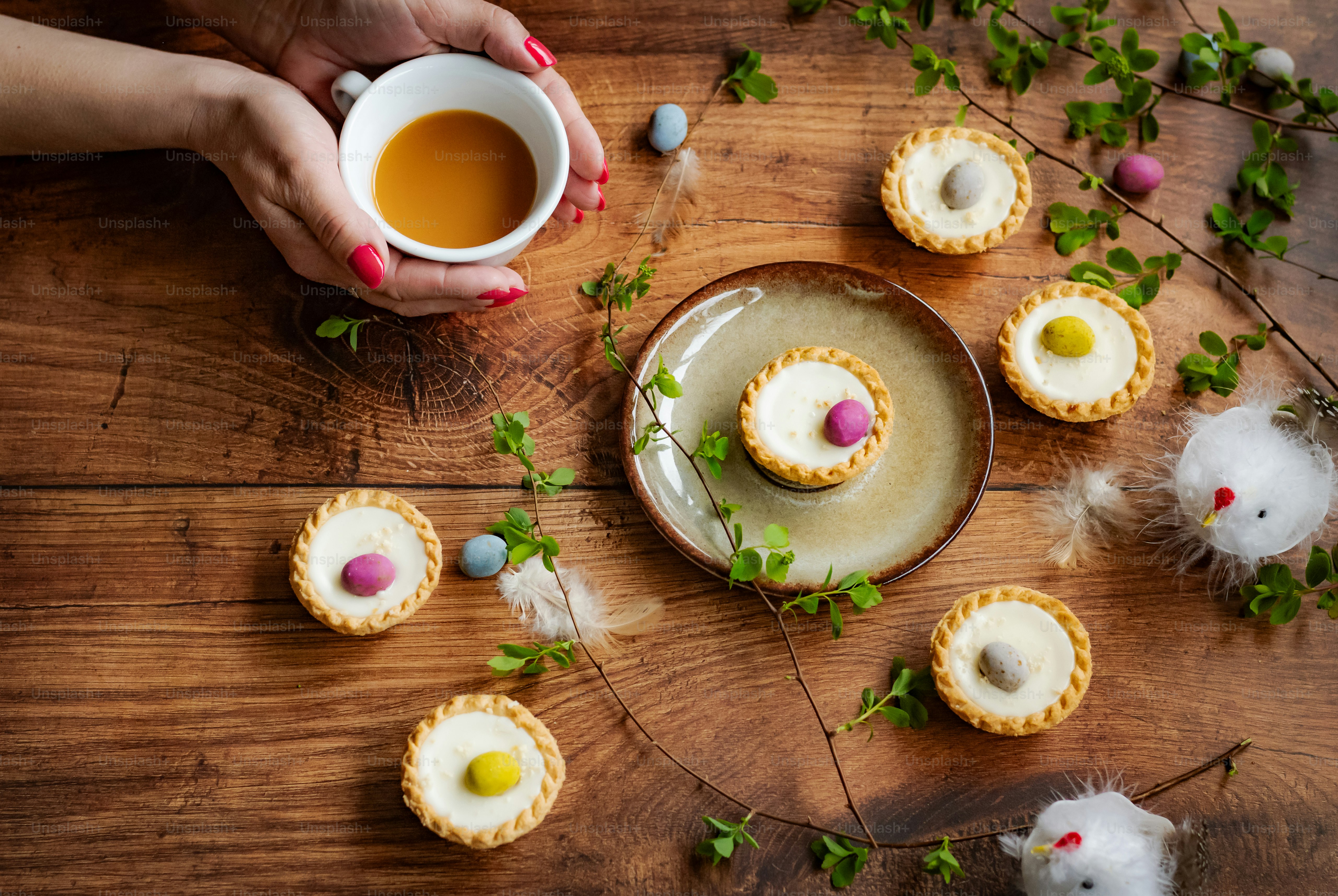 a person holding a cup of tea next to some cookies