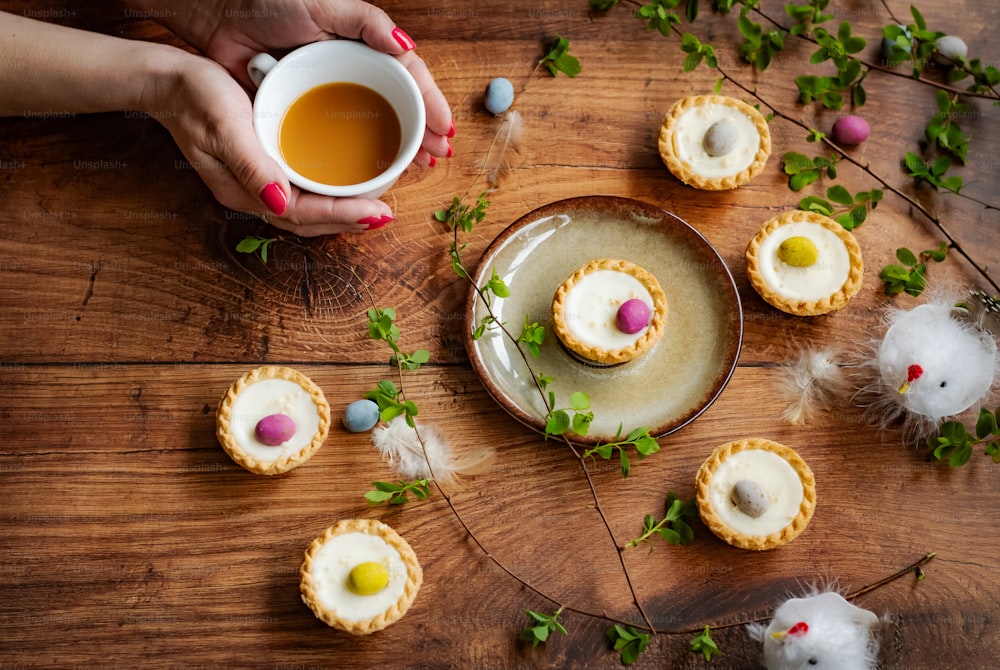 a person holding a cup of tea next to some cookies