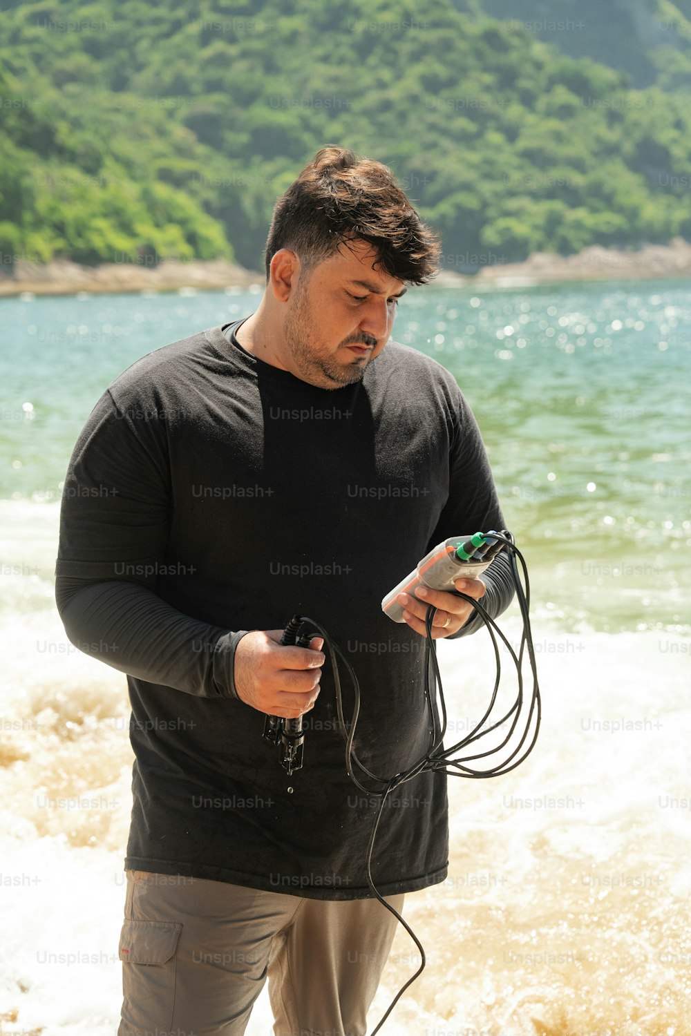 a man standing on a beach holding a cell phone