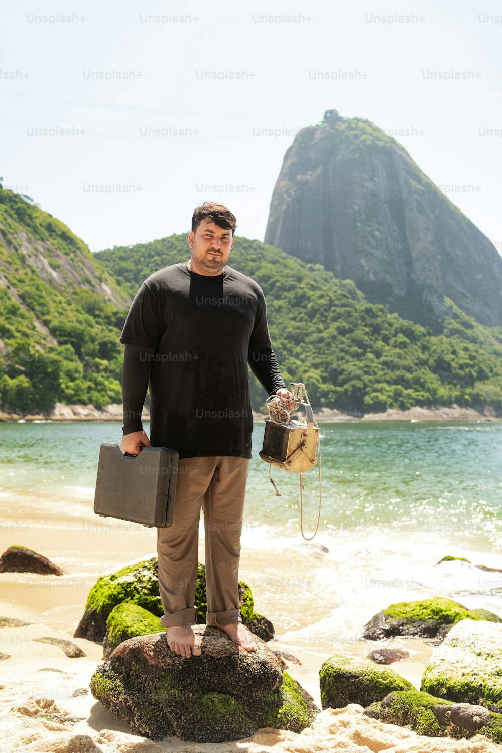 a man standing on top of a rock near the ocean