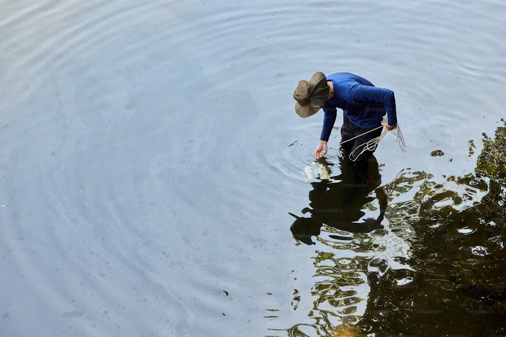 a man in a hat is wading in the water