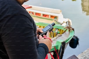 a man holding a cell phone next to a boat