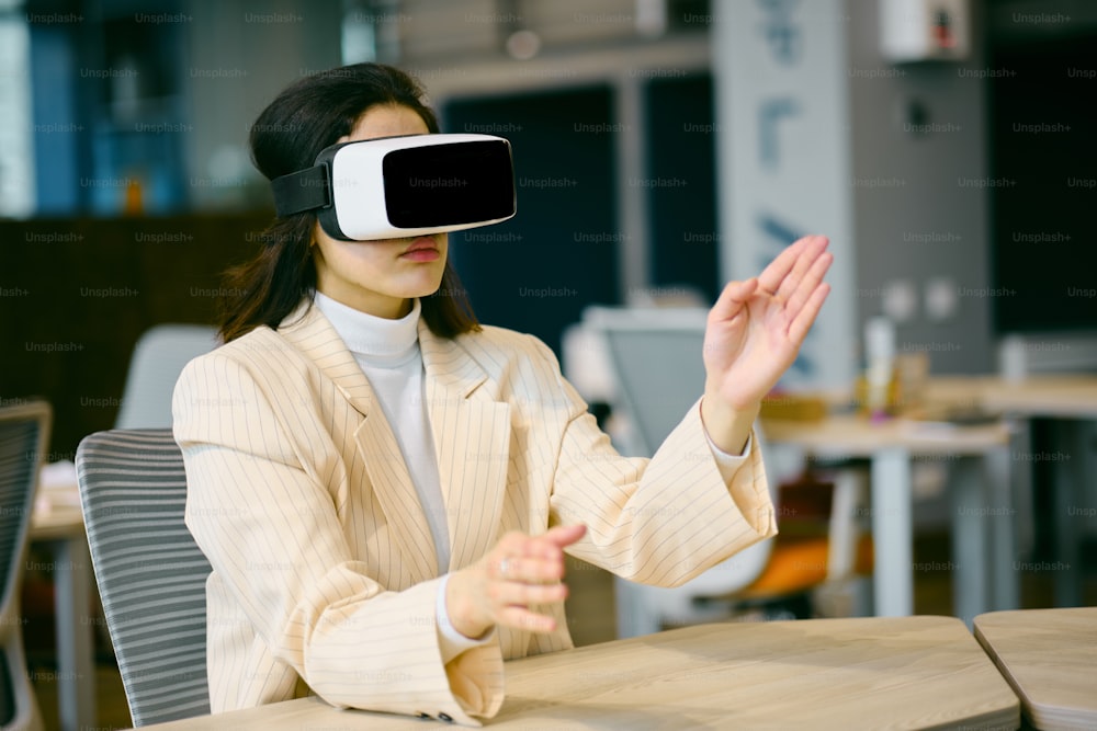 a woman sitting at a table wearing a virtual headset