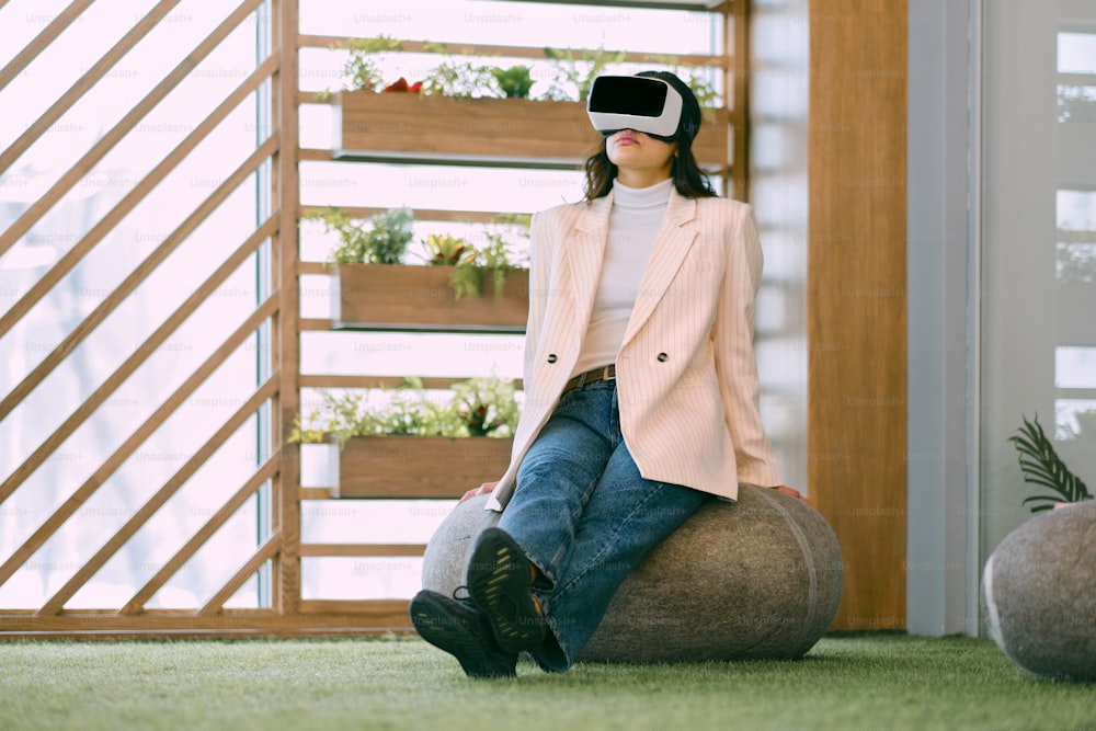a woman sitting on a bean bag chair wearing a virtual headset