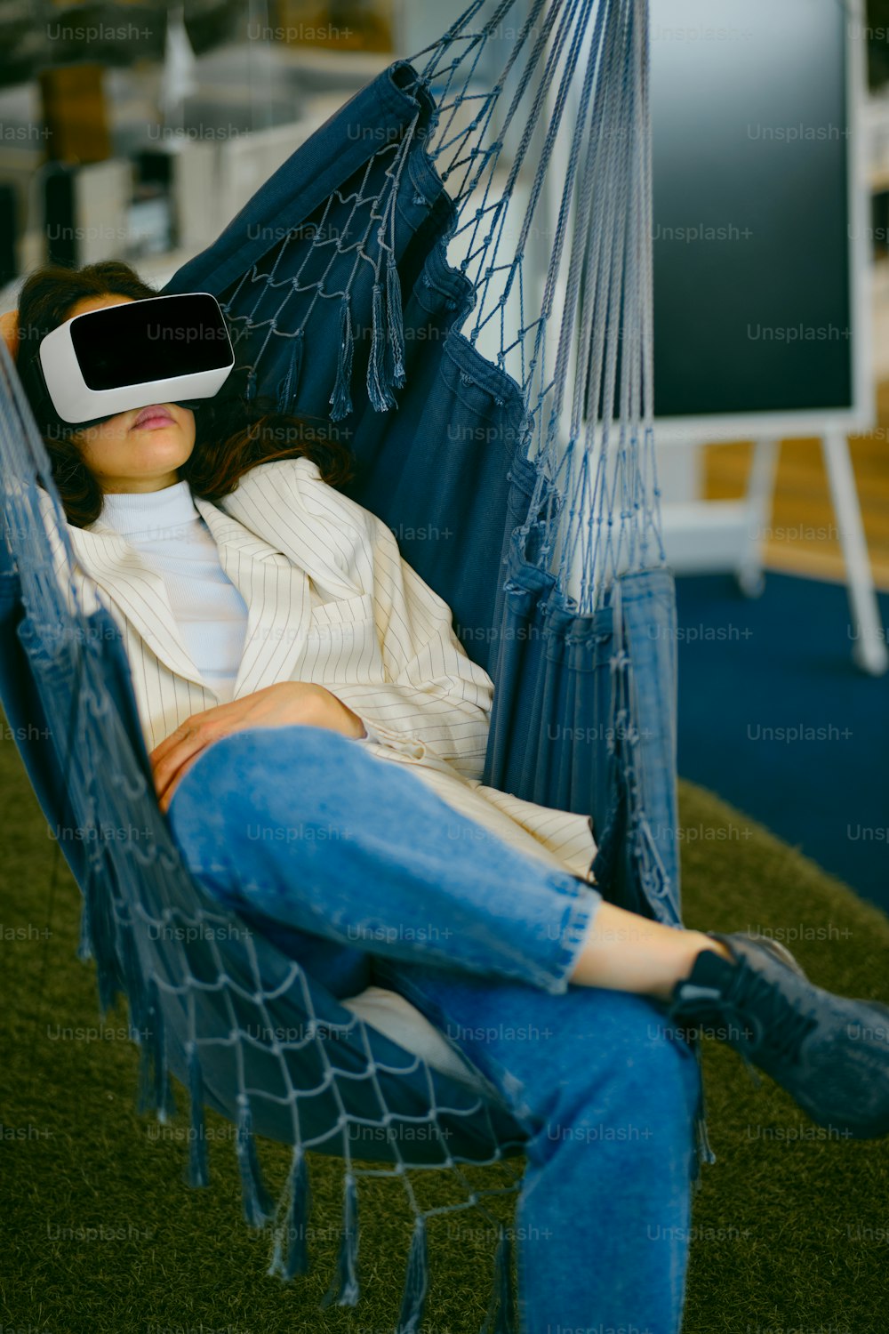 a woman sitting in a hammock wearing a virtual headset