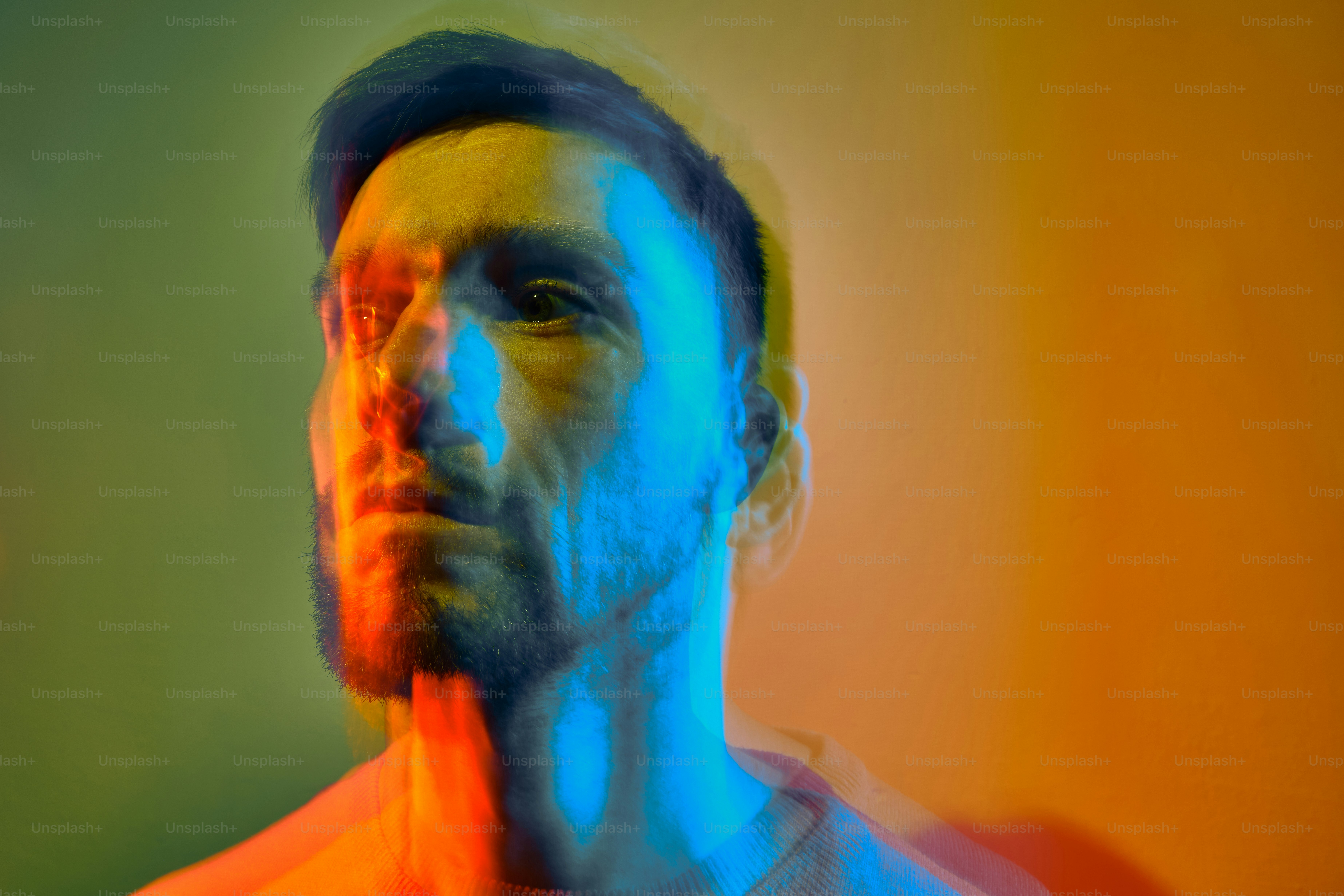 Ein Mann mit Bart steht vor einem bunten Hintergrund