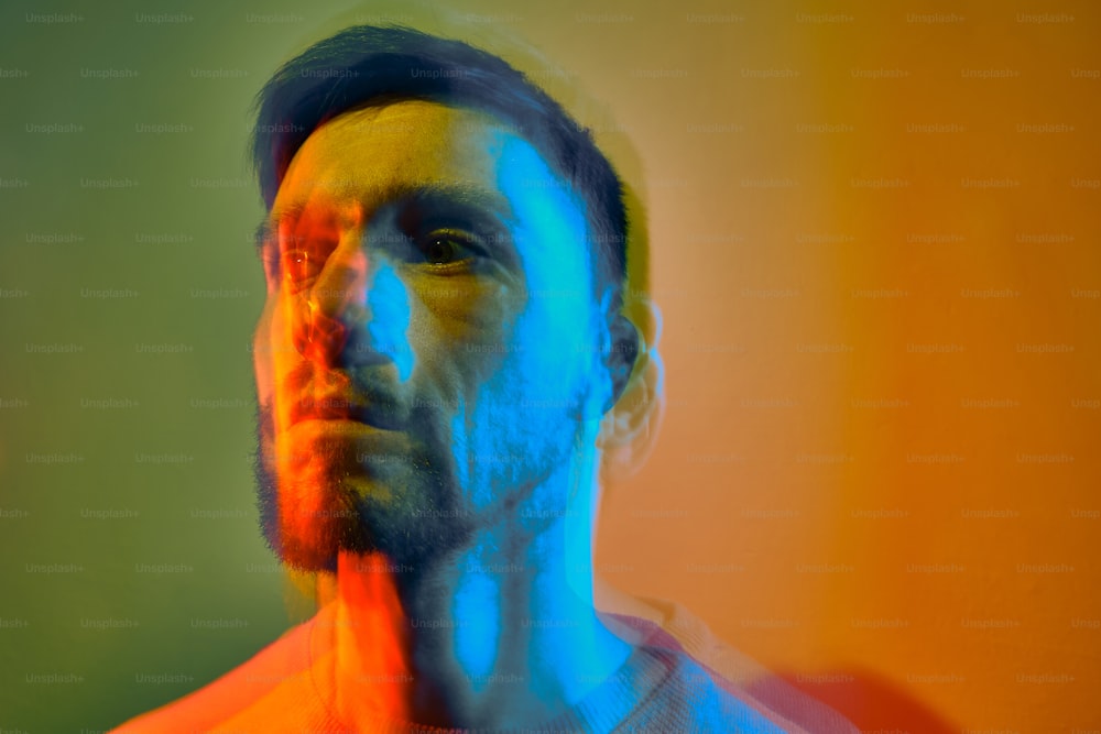a man with a beard standing in front of a multicolored background