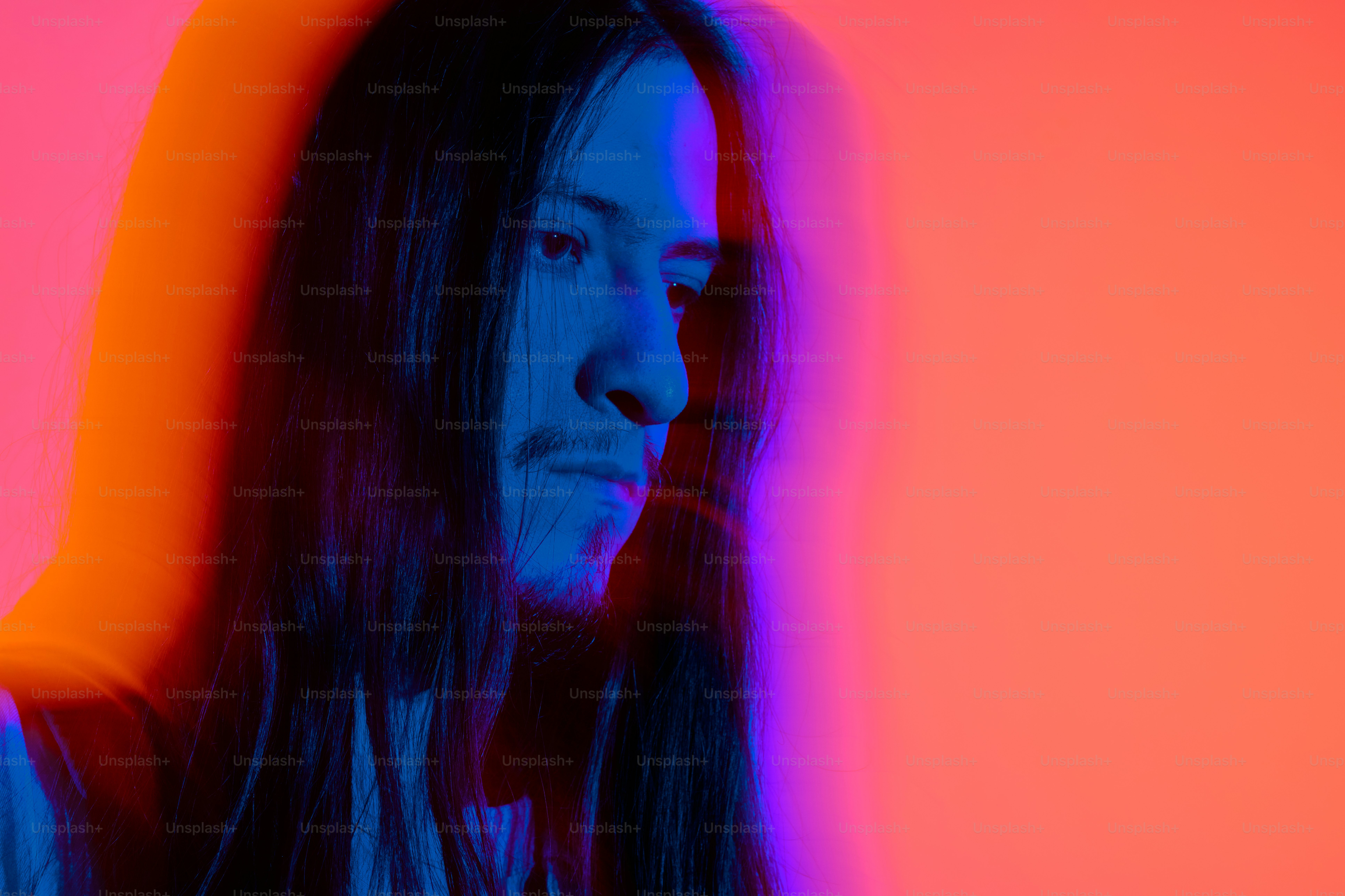 a man with long hair standing in front of a red and blue background