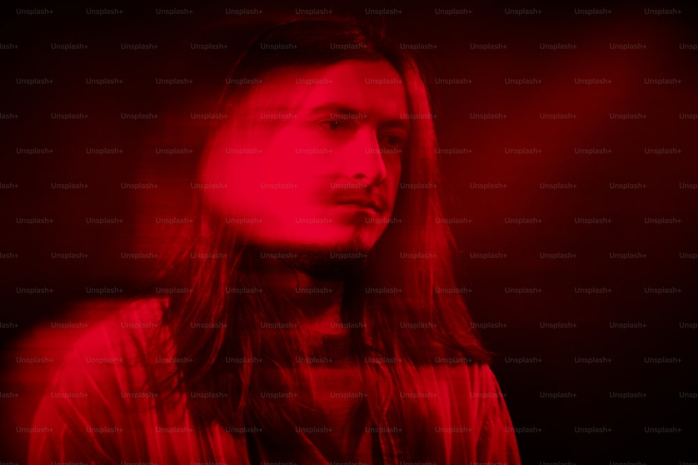 a man with long hair standing in a dark room