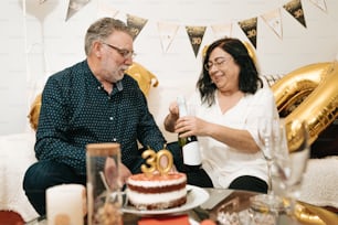 un uomo e una donna seduti a un tavolo con una torta
