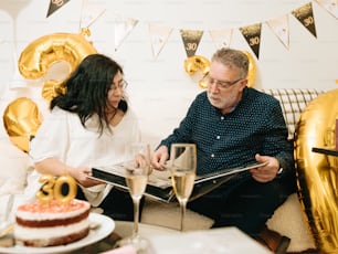 a man and woman sitting on a couch with a cake