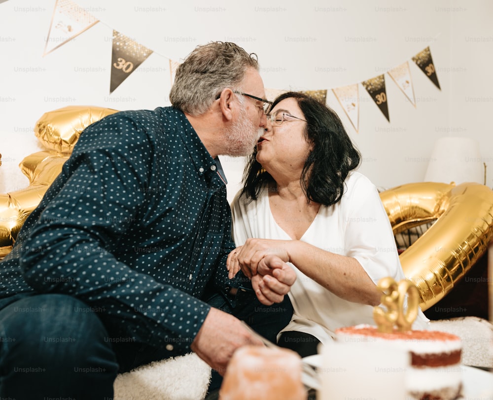 a man and a woman kissing in front of a cake